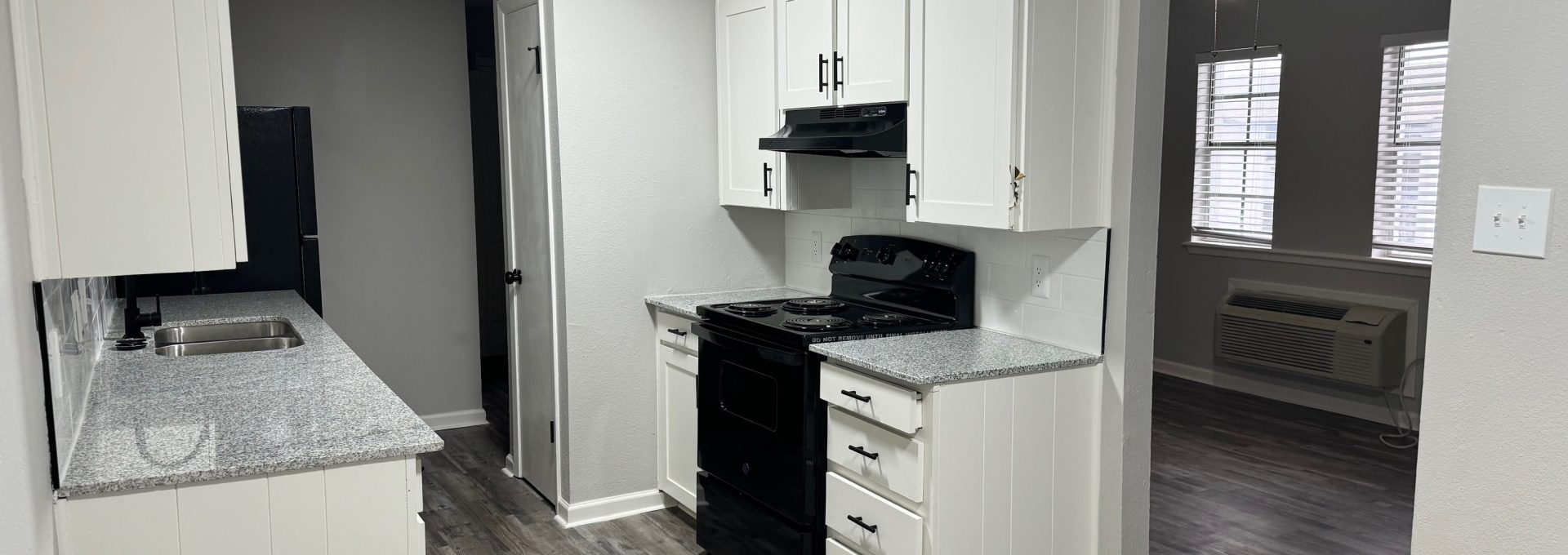 a kitchen with white cabinets and black appliances at The  Landing Apartments