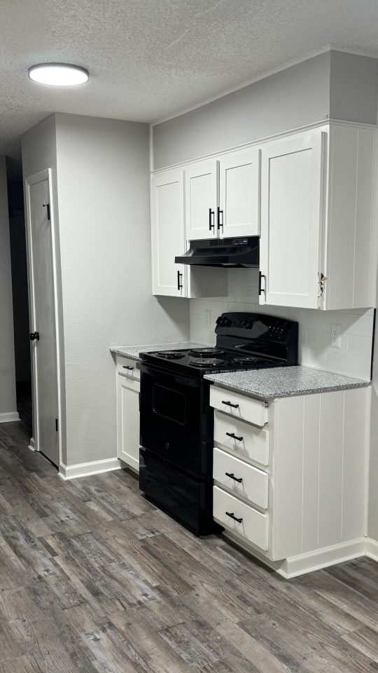 a kitchen with white cabinets and black appliances at The  Landing Apartments