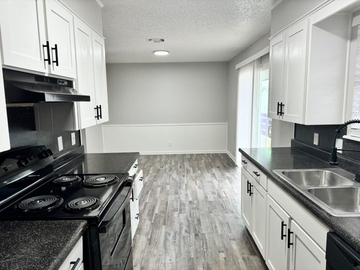 a kitchen with black appliances and white cabinets at The  Landing Apartments