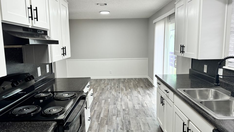 a kitchen with black appliances and white cabinets at The  Landing Apartments