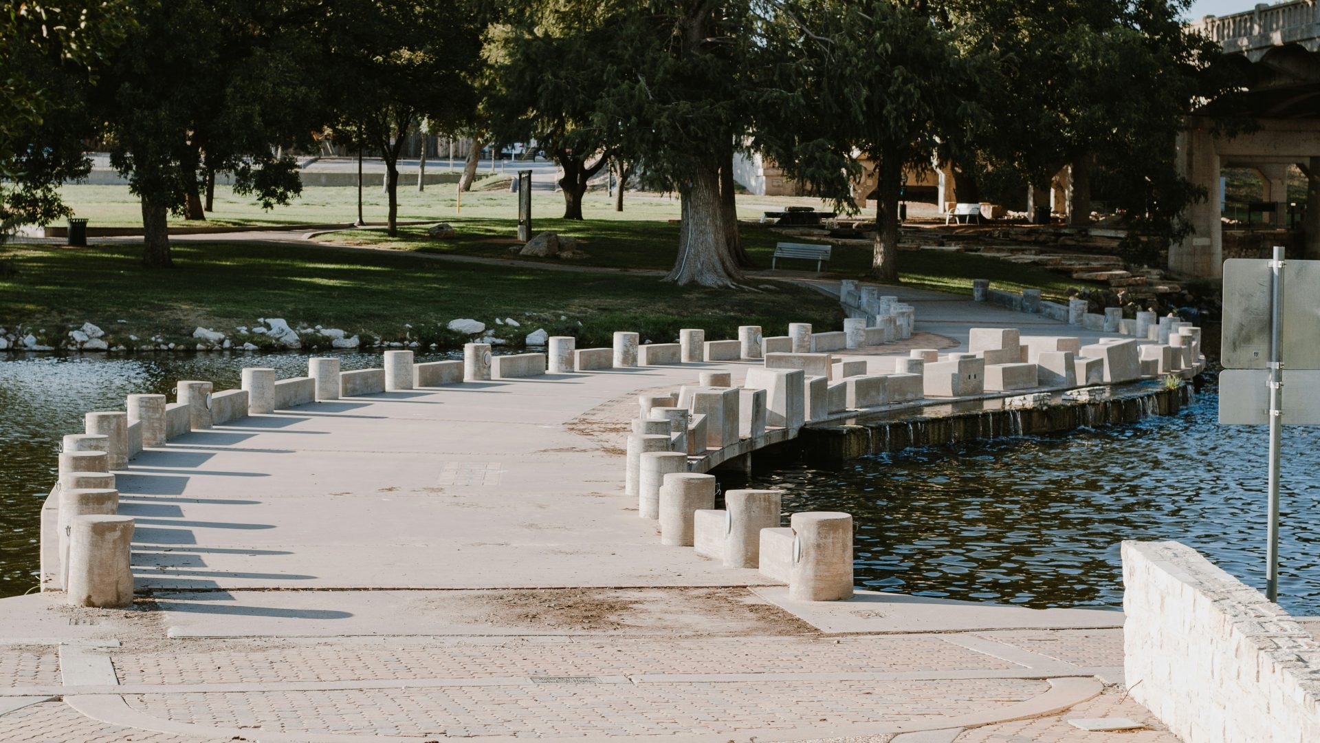 a walkway leading to a lake and a fountain at The  Landing Apartments