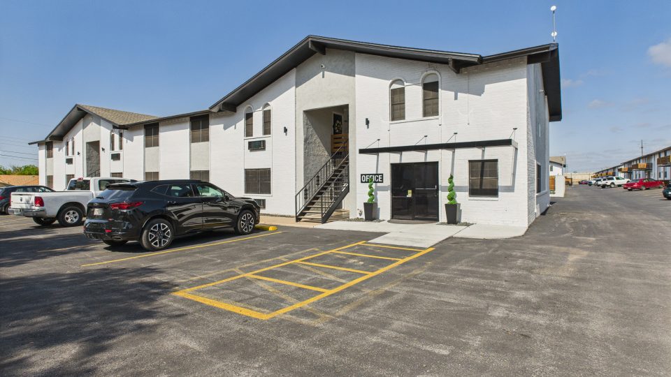 the exterior of an apartment building with parking lot at The  Landing Apartments