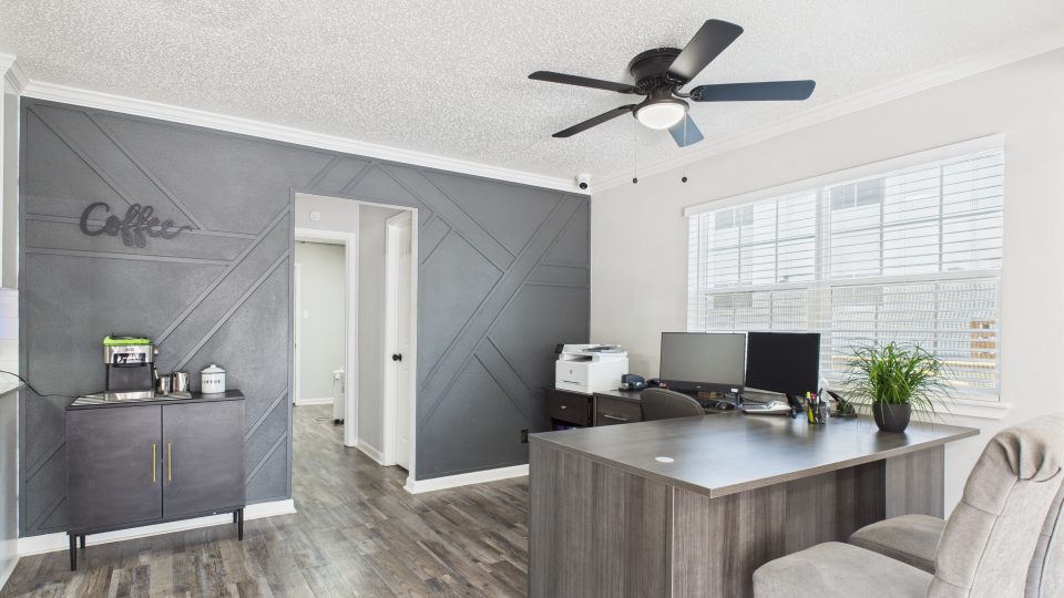 a home office with a gray ceiling and wood floors at The Landing Apartments